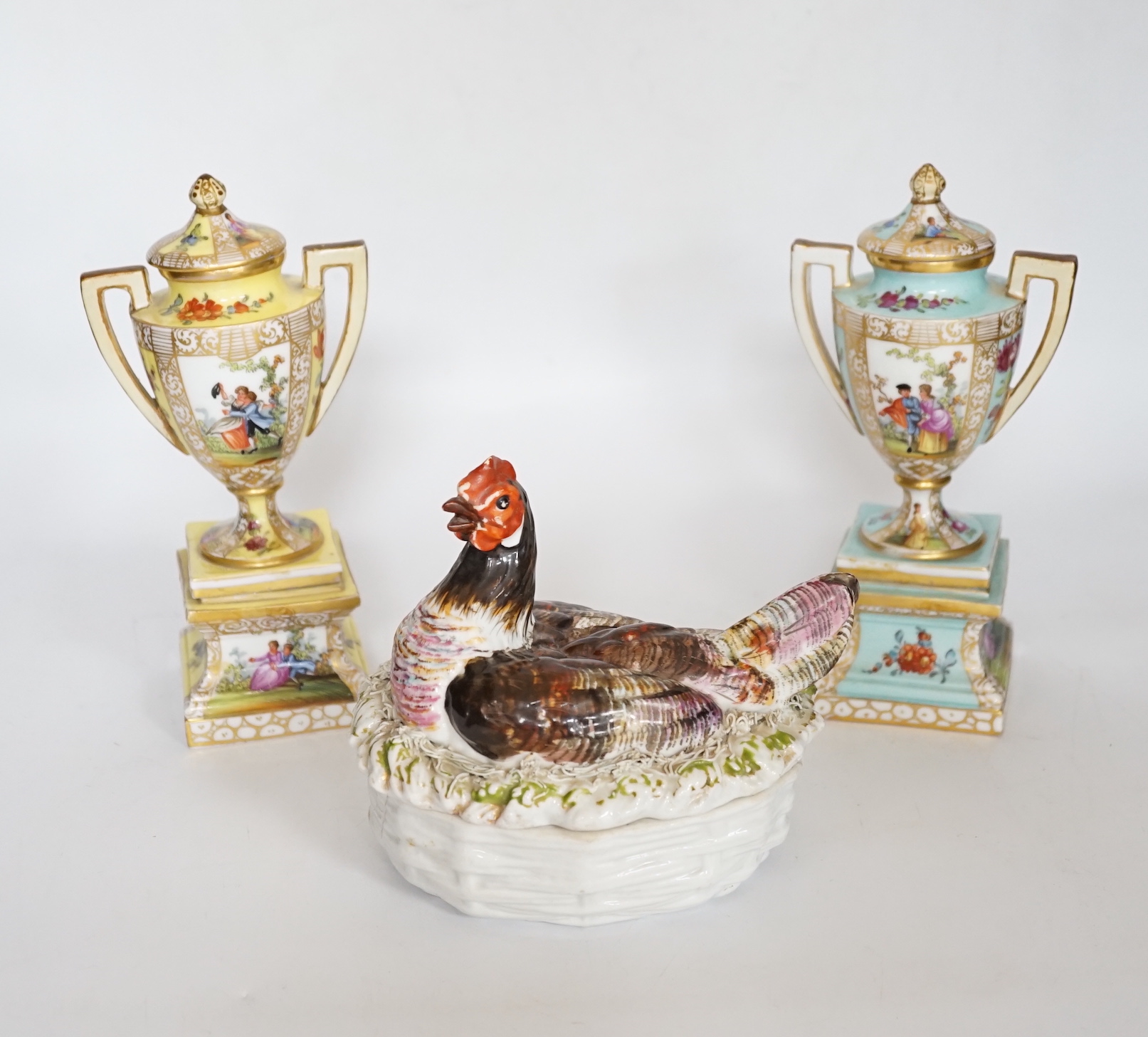 A pair of Dresden porcelain vases and covers (restored) together with a hen egg basket and cover, largest 19cm high (3)